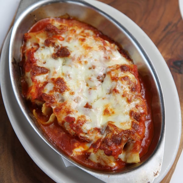 Baked ziti or lasagna in a metal dish with melted cheese and red sauce.
