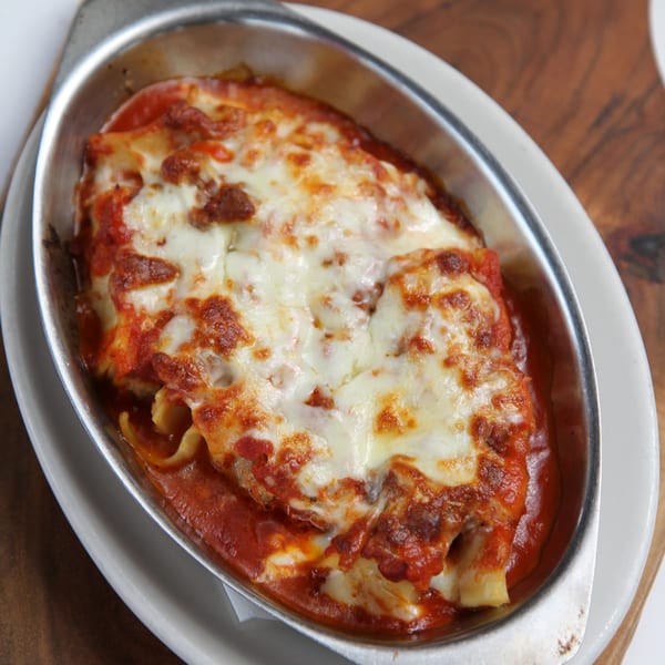 Baked ziti or lasagna with melted cheese and red sauce in a metal dish.