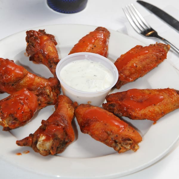 A plate of Fort Lee Pizzeria's buffalo wings arranged around a cup of ranch dressing.