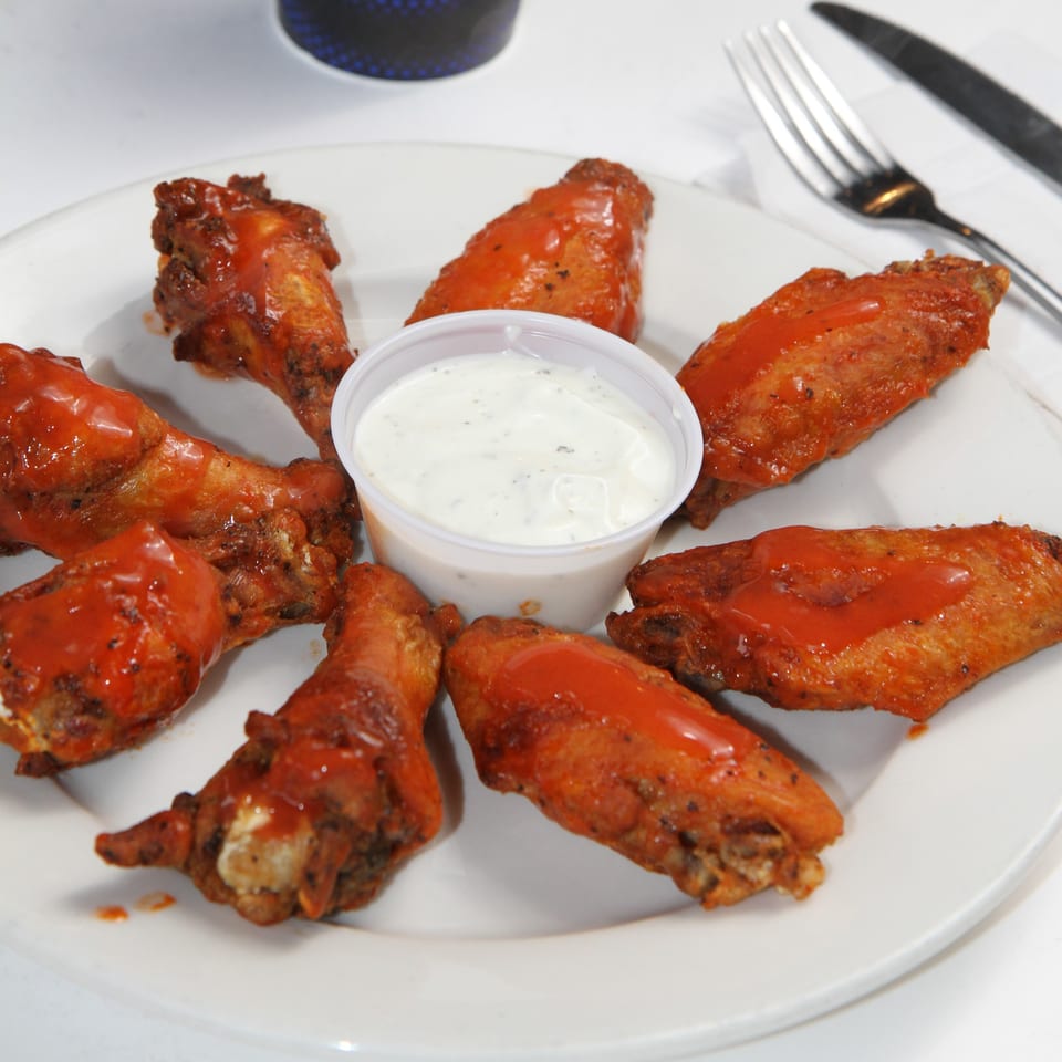 A plate of Fort Lee Pizzeria's buffalo wings arranged around a cup of ranch dressing.